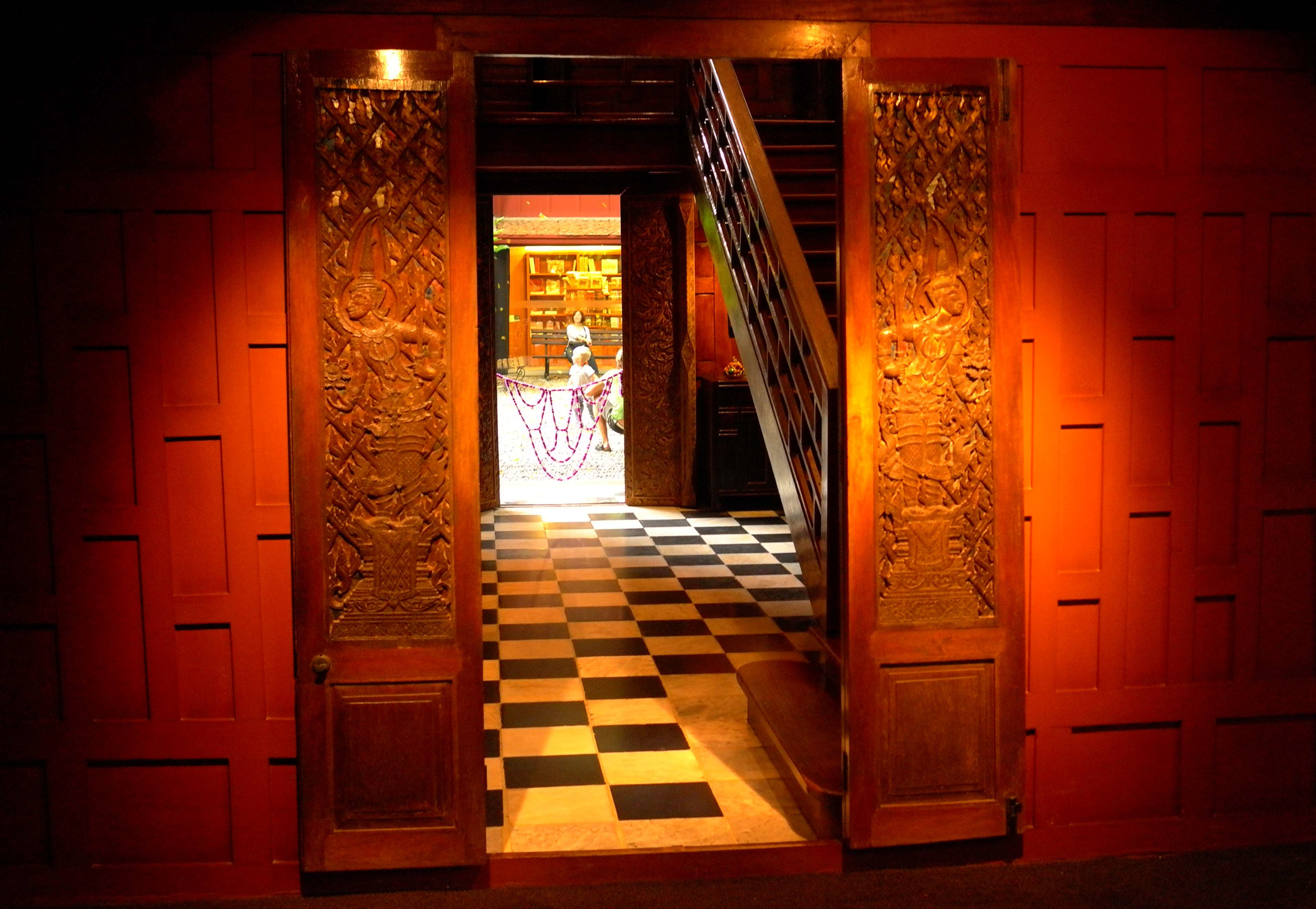 Detail of the entry hall of the Jim Thompson residence, showing interior stairway, black and white reclaimed Italian marble tiles and decorative carving on the doors (Photo Catherine Clover, 2013)